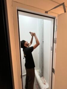 Engineer inspecting a service riser shaft behind an access panel